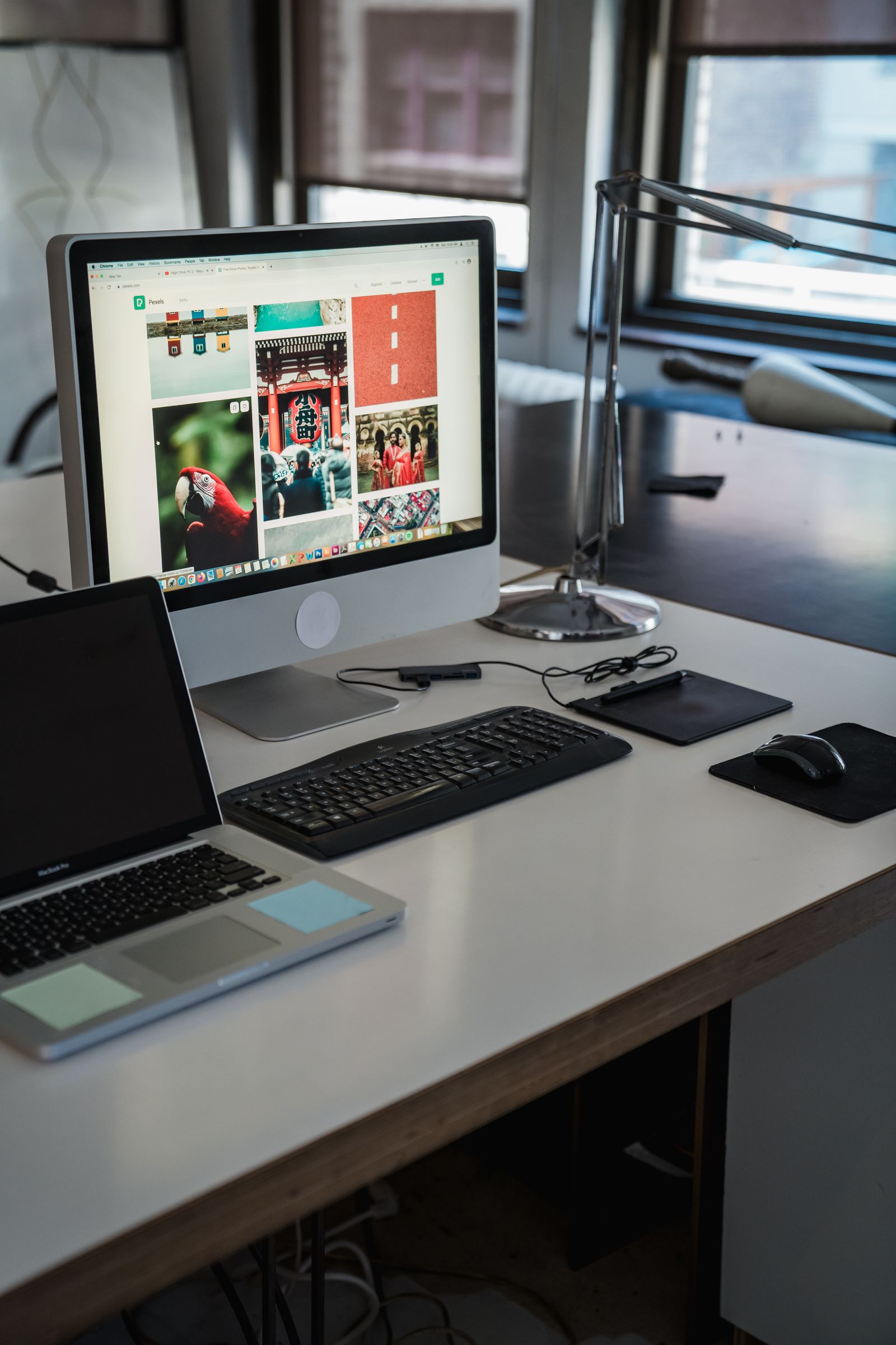 Arbeitsplatz mit Monitor, Laptop, Tastatur und Schreibtischlampe